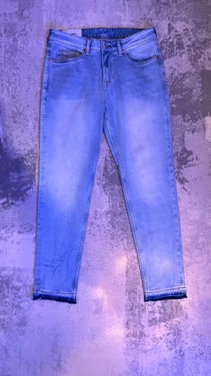 Ljusblå straight fit jeans ifrån HM  - Säljer ett par ljusblå raka jeans i storleken (31-32). fransig kant nedtill. Klassisk femficksmodell med dragkedjegylf och fin passform. Perfekta till sneakers för en avslappnad look.