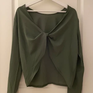  långärmad topp med omlott ryggöppning  - Säljer en grön långärmad topp med omlott ryggöppning från Boohoo i storlek 36. Andvänd fåtal ggr.