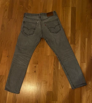 Grå Levi's 511 jeans straight fit - Säljer ett par grå Levi's 502 jeans med klassisk femficksdesign och raka ben. Jeansen har en snygg, neutral grå färg och är tillverkade i mjukt bomullsmaterial med lite stretch för extra komfort. Passar dig som gillar en clean och enkel look. Storlek w30 l31