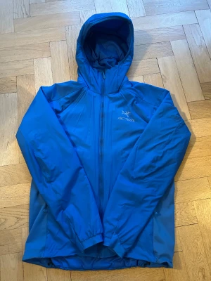 Blå vindjacka från Arc'teryx M - Snygg blå vindjacka från Arc'teryx med huva och hel dragkedja framtill. Perfekt för dig som gillar outdoor och vill ha en stilren jacka med skön passform. Pris är inte fast, så bjud gärna.