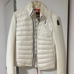 Vit pufferjacka från Parajumpers  - Snygg vit pufferjacka från Parajumpers med quiltad front, släta ärmar och coolt PJS-märke på axeln. Jackan har dragkedja, bröstficka med zip och sportig känsla. Behövs däremot tvättas. Storlek M 
