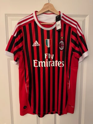 AC Milan Ibrahimović 11 Adidas tröja - Säljer en AC Milan-tröja med Ibrahimović #11. Klassiska röd-svarta ränder, vit krage, Adidas-logga och Fly Emirates-tryck. Lätt och ventilerande polyester.  Följ oss gärna på Instagram:    @kickstoreuf
