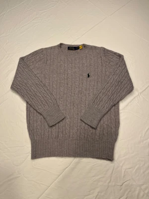 Grå kabelstickad tröja - Snygg grå kabelstickad tröja. Perfekt nu till de kallare dagarna. Har använts ett fåtal gånger med varsamhet. Liten i storlek så skulle rekommendera för storlek S. Skriv vid funderingar så svarar jag så snabbt som möjligt. Pris kan diskuteras!
