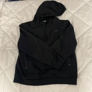 Svart hoodie från Nike XL (jr)  158-170cm - Svart hoodie från Nike i storlek XL 158-170cm, med klassisk huva och dragkedja framtill. Tröjan har långärmade ärmar och ett diskret Nike Swoosh på bröstet. Perfekt för chill eller träning, tillverkad i mjukt syntetmaterial för skön komfort.