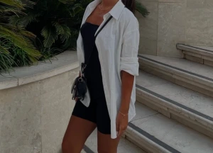 Vit oversized skjorta i bomull - Snygg vit oversized skjorta i bomull med klassisk krage och långa ärmar. Perfekt att bära öppen över ett linne eller klänning för en avslappnad och trendig look. Skjortan har en rak passform och knappar framtill.