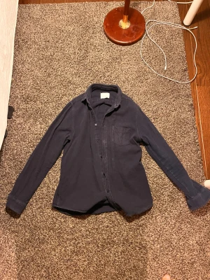 Mörkblå skjorta från Samsøe Samsøe - Mörkblå skjorta från Samsøe Samsøe i storlek M. Skjortan har klassisk krage, bröstficka och knappar framtill. Materialet är mjukt och känns som bomull, perfekt för en chill och stilren look. Färgen heter Night Sky Mel och passar till det mesta.