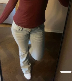 Bootcut ljusblå jeans med slitningar - Snygga bootcut jeans i ljusblå tvätt med slitningar framtill från weekday. Modellen har låg midja, klassiska fem fickor och bälteshällor. Jeansen är tillverkade i mjukt denim och har en lätt utsvängd passform nedtill för en cool retro vibe.