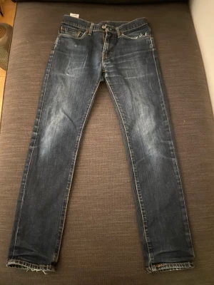 Levi's 511 W31 L32 - Snygga Levi's 511 jeans i mörkblå tvätt med slitna detaljer på bakfickorna och råa kanter vid bensluten. Modellen som är rak men lite mer åt slim hållet. Skriv om ni undrar över någonting.