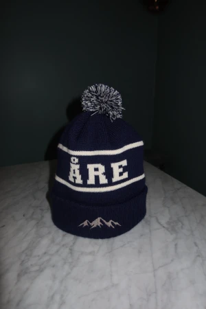 Åre mössa - Riktigt fräsch blå Åre mössa från SkiStyle UF✅. Framsidan har ÅRE-text och ett broderat bergmotiv. Stickad i mjukt material, otrolig kvalitet och perfekt för kalla dagar, skriv vid frågor eller funderingar!