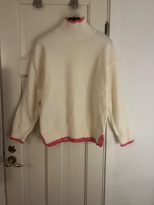 Vit polotröja med rosa detaljer - Säljer denna super fina tröjan från meet me there ur fillipas kollektion. 💓Den har rosa detaljer längst kanterna och har en hög krage. Tröjan har aldrig kommit till användning och är i storlek S/M 🫶❣️