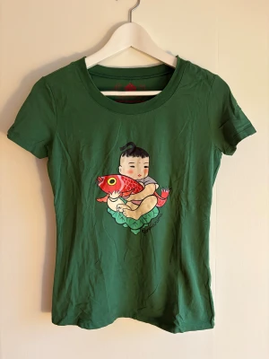 Grön t-shirt med tryck från Fornarina - Grön t-shirt från Fornarina med ett färgglatt tryck . T-shirten har rund halsringning och korta ärmar. Materialet är mjuk bomull med lite stretch för en bekväm passform.