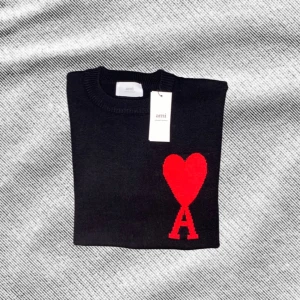 Ami Paris tröja - Svart stickad tröja från Ami med rund hals och ribbade muddar. På bröstet finns ett stort rött hjärta med bokstaven A under, vilket ger en unik och snygg look. Perfekt för dig som gillar stilrena detaljer och vill sticka ut lite extra. Den är helt ny med prislapp. Kom gärna med förslag omkring den och frågor!🙂