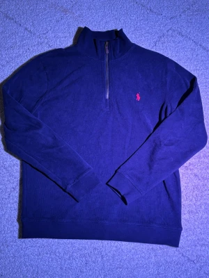 Ralph Lauren halv-zip - Säljer denna feta fjärdedels-zipen från Ralph Lauren i marinblått för bara 299 i storlek M. Tröjan har en snygg och unik design. Den är i väldigt fint skick och finns inte mycket tecken på användning eftersom att den bara är använd ett fåtal gånger.  Den är redo att hitta ett nytt hem! Fråga gärna om ni vill ha fler bilder eller mer information