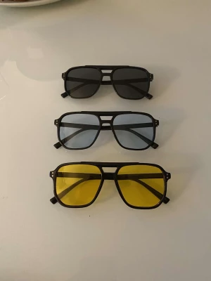 Tre par retro pilotglasögon - Säljer tre par snygga pilotglasögon med svart ram och olika färgade linser: ett par med mörka linser, ett med ljusblå linser och ett med gula linser. Perfekt för dig som vill variera din stil och sticka ut med coola accessoarer.