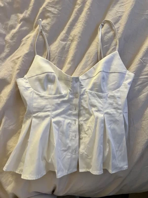 Fin vit blus top från Zara  - Jätte fin top från Zara som är vid med knappar där fram toppen har sjusterbara band och är andvänd 1 gång