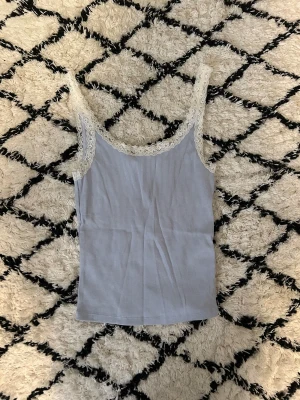 Ljusblå ribbad linnetopp från H&M - Supersöt ljusblå linnetopp från H&M med ribbad struktur och spetskant i vitt runt halsringningen och axelbanden.  🥰🫰🏼