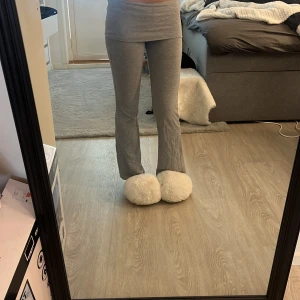 Grå bootcut mjukisbyxor Gina Tricot - Grå mjukisbyxor från Gina Tricot med bootcut-ben och bred linning. Byxorna är i mjukt bomullsmaterial och har en bekväm passform som sitter snyggt över höfterna. Perfekta för en chill och avslappnad stil.