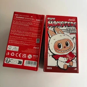 The Monsters Vinyl Blind Box Face Coca-Cola Edition - Samlarfigur från Pop Mart, The Monsters Vinyl Blind Box Face Coca-Cola Edition. Oöppnad originalförpackning, passar samlare och fans av unika designer. Kartongen är i gott skick med minimalt slitage. Perfekt som present eller till din samling.