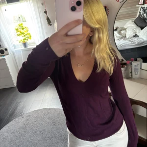 Mörklila v-ringad stickad tröja - Säljer en mörklila stickad tröja med v-ringning och långa ärmar. Tröjan har en slim passform och är perfekt för dig som gillar en enkel men snygg stil. Materialet är mjukt och skönt mot huden.