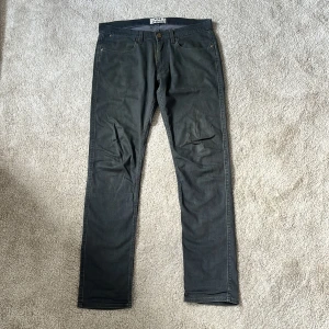  Acne Studios jeans - Snygga mörkgrå jeans från Acne Studios med klassisk femficksdesign och raka ben. Jeansen har metallknappar med logga och bälteshällor. Tillverkade i ett mjukt bomullstyg med en stilren look som passar till det mesta. Jeansen har en distressed tvätt och diskreta detaljer. Midjan är ganska låg och är i modellen Max Darko. Storlek: 30/32