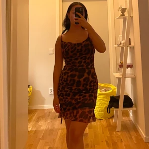 Leopardmönstrad kort klänning - Säljer en snygg kort klänning med leopardmönster och smala axelband. Klänningen har en figurnära passform och är perfekt för dig som vill sticka ut. Materialet känns lätt och följsamt mot kroppen. Perfekt för dig som gillar trendiga och djärva looks.