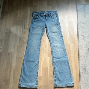 Ljusblå bootcut jeans Gina Tricot - Snygga ljusblå jeans från Gina Tricot i klassisk bootcut-modell. Jeansen har fem fickor, dubbla knappar i midjan och är tillverkade i mjukt denimtyg. 