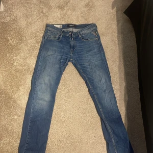 Blå Replay jeans straight fit - Säljer ett par klassiska blå jeans från Replay med raka ben och femficksmodell. Jeansen har snygga slitningar och detaljerade bakfickor med Replay-logga. Perfekta för dig som gillar en tidlös och avslappnad stil. Storlek 29