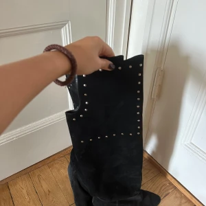 Svarta mockastövlar med nitar - Snygga svarta stövlar i mocka med coola silvriga nitar längs skaftet. De har spetsig tå och låg klack, vilket ger en edgy vibe. Perfekta för dig som vill sticka ut med detaljer och gillar boots med lite attityd.