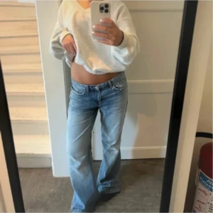 Ljusblå bootcut jeans låg midja - Säljer ett par ljusblå jeans med bootcut-modell och låg midja. Jeansen har klassisk femficksdesign och är tillverkade i denim. Perfekta för dig som gillar en avslappnad och trendig look. Passar 36/38. Är uppsydda ! Midjemått: 42 innerbens: 74