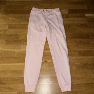 Ljusrosa mjukisbyxor med snörning - Säljer ett par ljusrosa mjukisbyxor med elastisk midja och snörning. Byxorna har ribbade muddar vid bensluten och är tillverkade i mjukt bomullsmaterial. Perfekta för en chill och avslappnad stil.