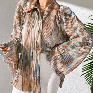 Randig plisserad skjorta med volangärm - Säljer en unik skjorta med plisserat tyg och randigt mönster i beige, blått och brunt. Skjortan har bred krage, knappar framtill och långa volangärmar som ger en cool och trendig look. Perfekt för dig som vill sticka ut med din stil.