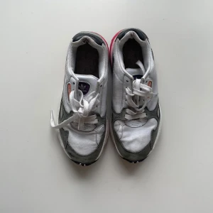 Adidas sneakers vit/grå/rosa - Säljer ett par Adidas sneakers i vitt, grått och rosa med cool retrostil. Skorna har chunky sula med rosa och blå detaljer, mesh och mocka-paneler samt snörning. Skriv om ni har frågor!🤍🩶🩷