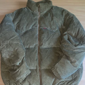 Olivgrön pufferjacka från Levi's - Säljer en ljusbrun  pufferjacka från Levi's i manchester. dragkedja framtill och breda kanaler för en riktigt fet look. Materialet är mjukt och ger en cool vintagekänsla. Perfekt för dig som vill sticka ut i höst och vinter jackan passar perfekt för en kall vinter håller värmen super bra ny pris ligger den på mellan 1700-1900 men är villig att sälja den för 1200 går även förhandla om pris  den har används en gång så är splitter ny