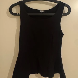 Svart linnetopp från Bik Bok - En stilren svart linnetopp från Bik Bok i storlek XS. Toppen har breda axelband, rundad halsringning och lätt utsvängd nederkant. Perfekt att matcha med jeans eller kjol för en enkel och snygg look.