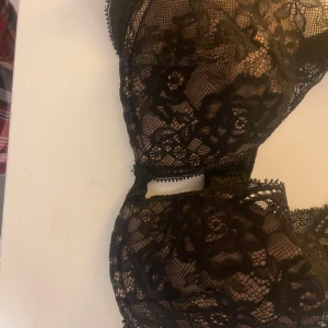 Svart spetskorsett från Intimissimi - Säljer en svart korsett från Intimissimi med vacker blommig spets och tunna axelband. Modellen har genomgående spetsdetaljer och en liten rosett framtill. Perfekt för dig som gillar en feminin och elegant stil.