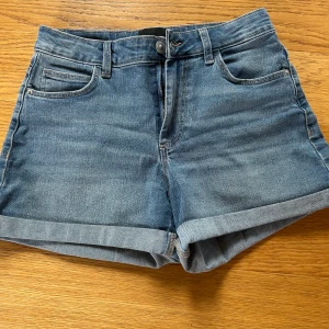 Blå jeansshorts från Pieces - Snygga blå jeansshorts från Pieces med klassisk femficksdesign och uppvikta benslut. Modellen är högmidjad och har knapp och dragkedja framtill. Pris går att diskuteras!