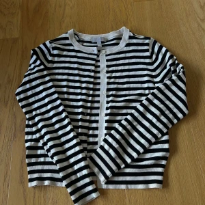 Randig kofta från H&M, svart och vit - Snygg randig kofta från H&M i svart och vitt med rund halsringning och knappar framtill. Använd 2 ggr. Pris går att diskutera!