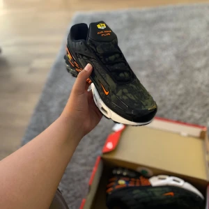 Nike Air Max Plus svart/orange sneakers - Köpte dem för 2500 från footlocker men tog aldrig på dem. Nike Air Max Plus sneakers i svart och mörkgrön med orange detaljer och vit sula. Snyggt camo-inspirerat mönster på ovandelen, tydlig Air Max-dämpning och coola grafiska linjer på hälen. Perfekta för dig som vill sticka ut med streetstyle-vibe. Priser kan diskuteras 