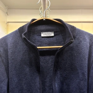 Marinblå kofta från Gran Sasso - Snygg marinblå kofta från Gran Sasso med hel dragkedja framtill. Tröjan är stickad i mjukt material och har ribbade muddar vid ärmslut och nederkant. Perfekt för lager-på-lager och stilren look.  Storlek : S