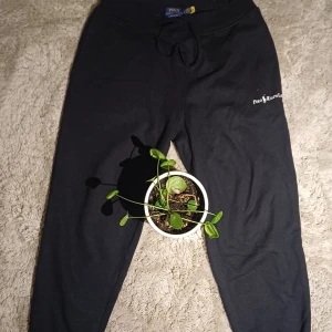 Svarta mjukisbyxor Polo Ralph Lauren - Svarta mjukisbyxor från Polo Ralph Lauren med broderad logga på benet. Byxorna har dragsko i midjan och är i mjukt bomullsmaterial. Avslappnad passform och klassisk stil, perfekta för chill dagar eller när du vill vara bekväm.