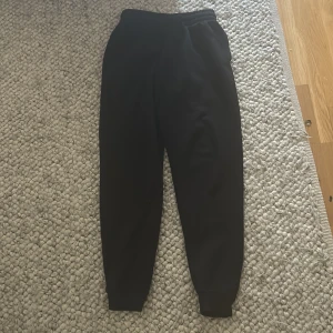 Svarta mjukisbyxor med resår - Svarta mjukisbyxor med resår i midjan och muddar vid bensluten. Perfekta för chill dagar eller när du vill vara extra bekväm. Klassisk passform och mjukt material som känns skönt mot huden.