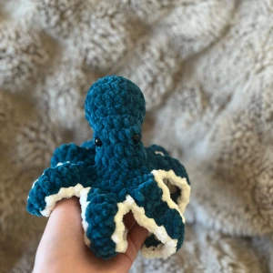 Virkad bläckfisk  - Nu säljer jag denna super gulliga bläckfisk 🦑 Passar perfekt till dekoration eller som ett litet gosedjur💕Den är ca 10 cm hög. Detta gosedjur har säkerhets ögon som inte rekommenderas för barn under 3 år så ha detta i åtanke vid köp! Viktigt: färgen är egentligen mer grön blå än det ser ut på bilderna! 