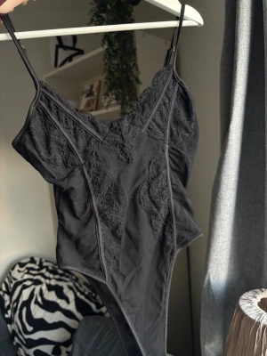 Svart spetsbody - Snygg svart string body i spets från NaaNaa. Inga tecken på användning.