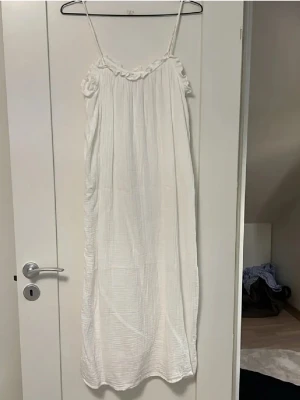 Två somriga långklänningar med smala band - Säljer två luftiga långklänningar med smala axelband och volangdetaljer upptill. Ena klänningen är helvit och den andra har blåvita ränder. Perfekta för varma dagar och har en avslappnad passform. Pris 50kr för båda klänningar💕