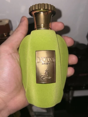 Voux Zingy parfym från Emir - Unik parfymflaska från Emir, modellen Voux Zingy. Flaskan är klädd i limegrönt material med en guldfärgad metallkork och en guldfärgad etikett framtill. Modern och iögonfallande design som sticker ut i parfymhyllan.
