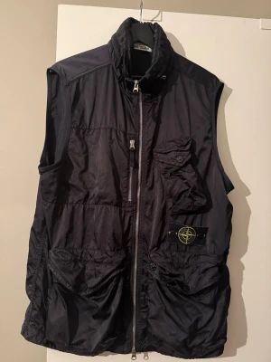 Stone Island väst Nylon Raso-TC - Snygg svart väst från Stone Island med hög krage, dragkedja framtill och flera praktiska fickor. Knappt använd och i rejält bra skick, nypris 9500kr