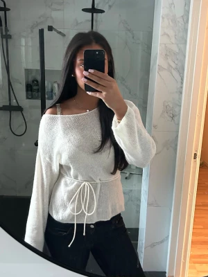 Vit stickad tröja med knytdetalj - Säljer denna jättesköna tröja med knyte i mitten från bikbok. Tröjan är i nytt skick och endast använd en gång.