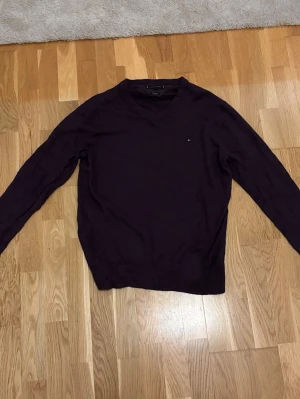 Mörklila stickad tröja Tommy Hilfiger - Bomull Kashmir tröja ifrån Tommy Hilfiger. Tröjan har långa ärmar och ribbade muddar vid ärmslut och nederkant. Perfekt för lager-på-lager-stil.
