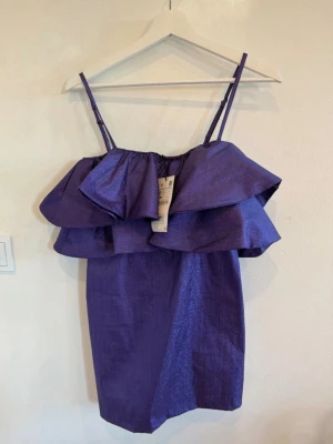 Lila volangklänning med smala axelband - Säljer en så snygg lila glittrande klänning från Zara i storlek S. Den är helt ny med prislapp. Perfekt till olika fester, temafester som capitol tema eller liknande. Den har volanger upptill och justerbart band.