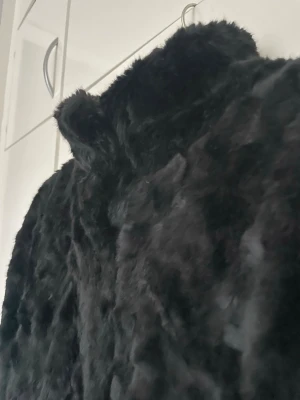 Svart pälsjacka Tiger of Sweden - Säljer en svart fuskpälsjacka med hög krage och mjuk, fluffig päls. Jackan har en snygg, klassisk rak passform och är perfekt för kalla dagar. Enkel och stilren design som ger en lyxig känsla. Dold knäppning och kan knäppas hela vägen upp längs halsen. 